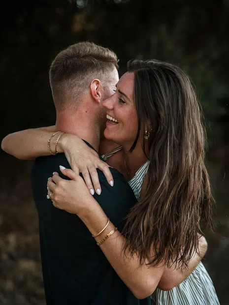 Un couple s'enlace chaleureusement, la femme sourit avec joie en tenant l'homme.