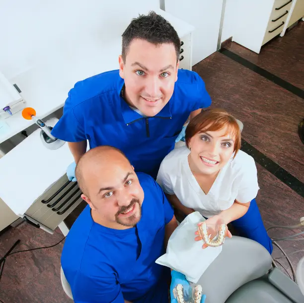 Équipe de dentistes souriants dans un laboratoire avec des prothèses dentaires à la main