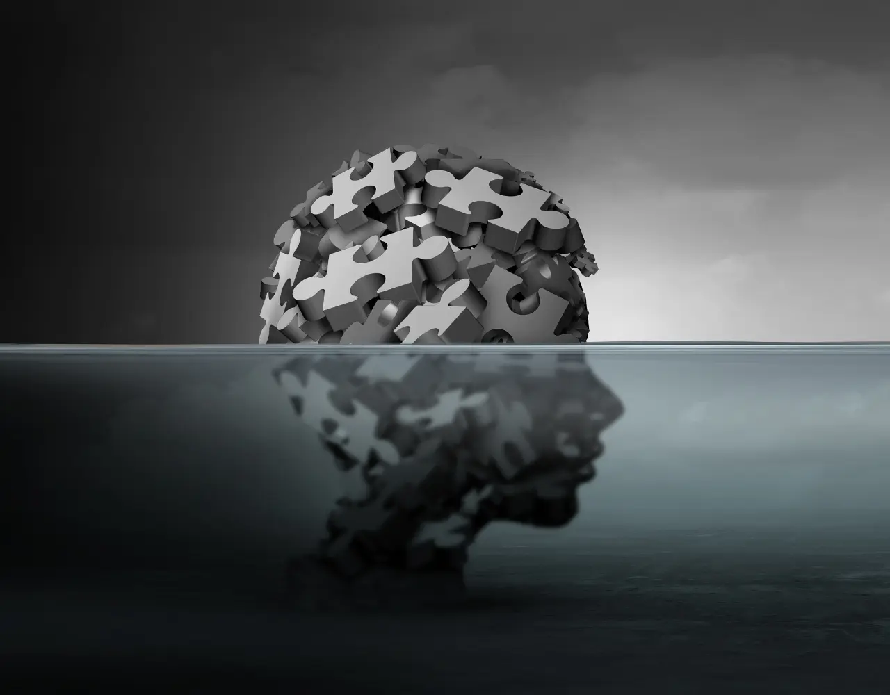 Cerveau en forme de puzzle reflété dans l’eau en silhouette humaine, illustrant la complexité de l’inconscient et du bien-être mental