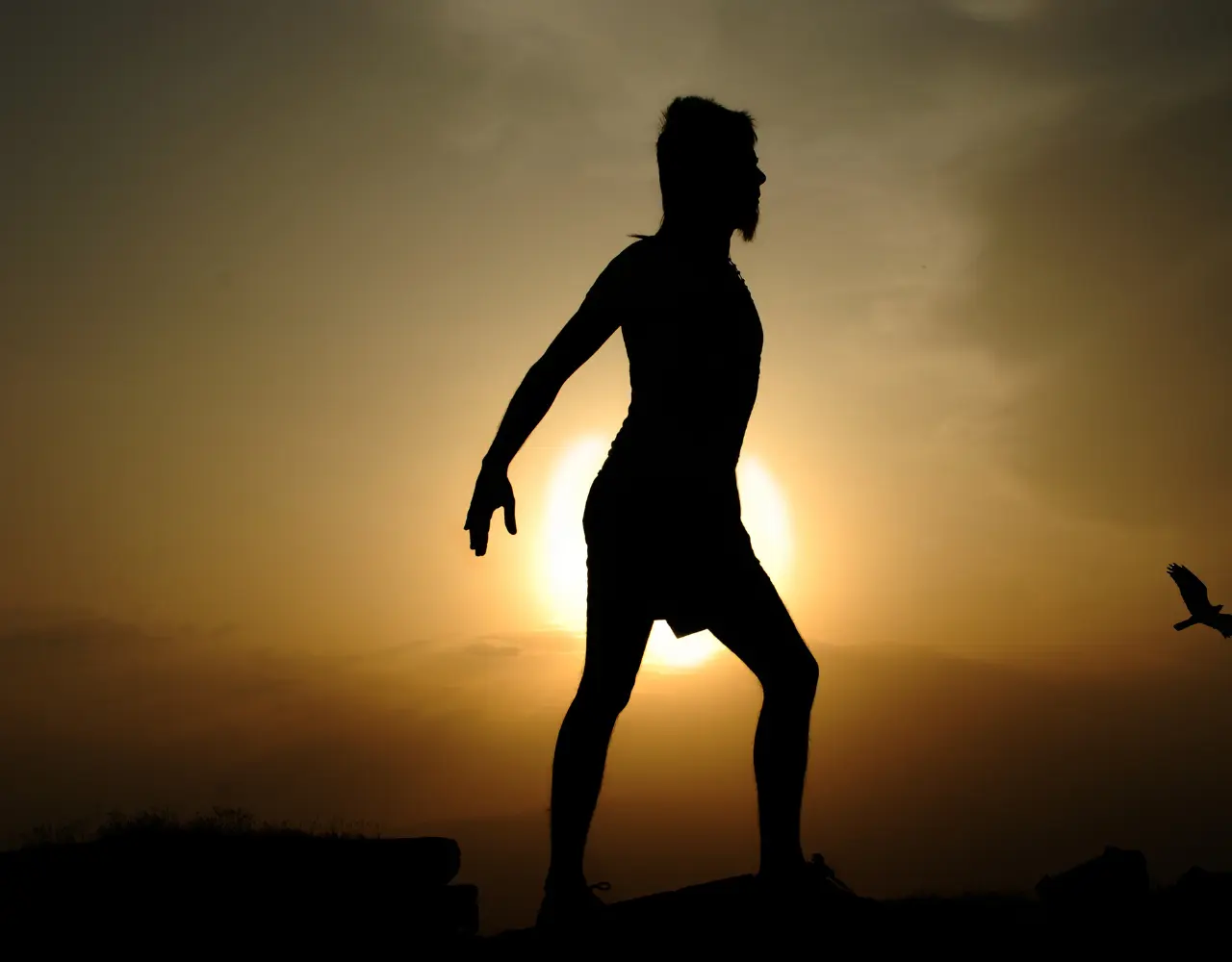 Silhouette d’une personne en posture de yoga au lever du soleil, symbolisant l’harmonie entre le corps, l’esprit et l’énergie