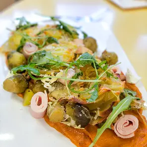 Tartine garnie de légumes grillés colorés, rondelles de radis roses et roquette fraîche sur pain grillé