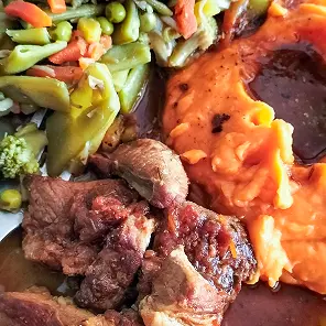 Assiette de viande grillée tranchée accompagnée de légumes sautés et de purée de patate douce orange