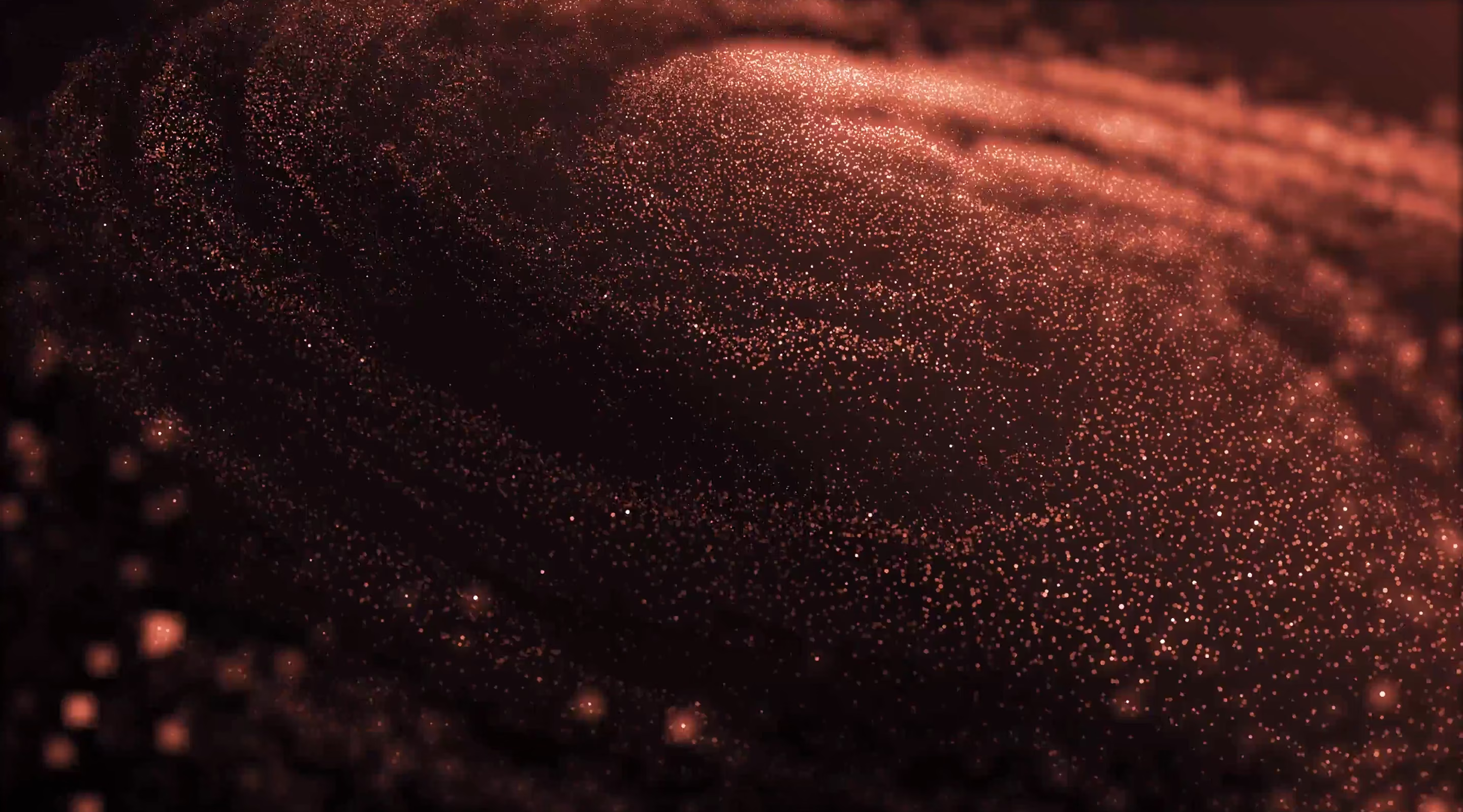 Un nuage de particules lumineuses orange dispersées sur un fond sombre, créant un effet de vague abstraite.