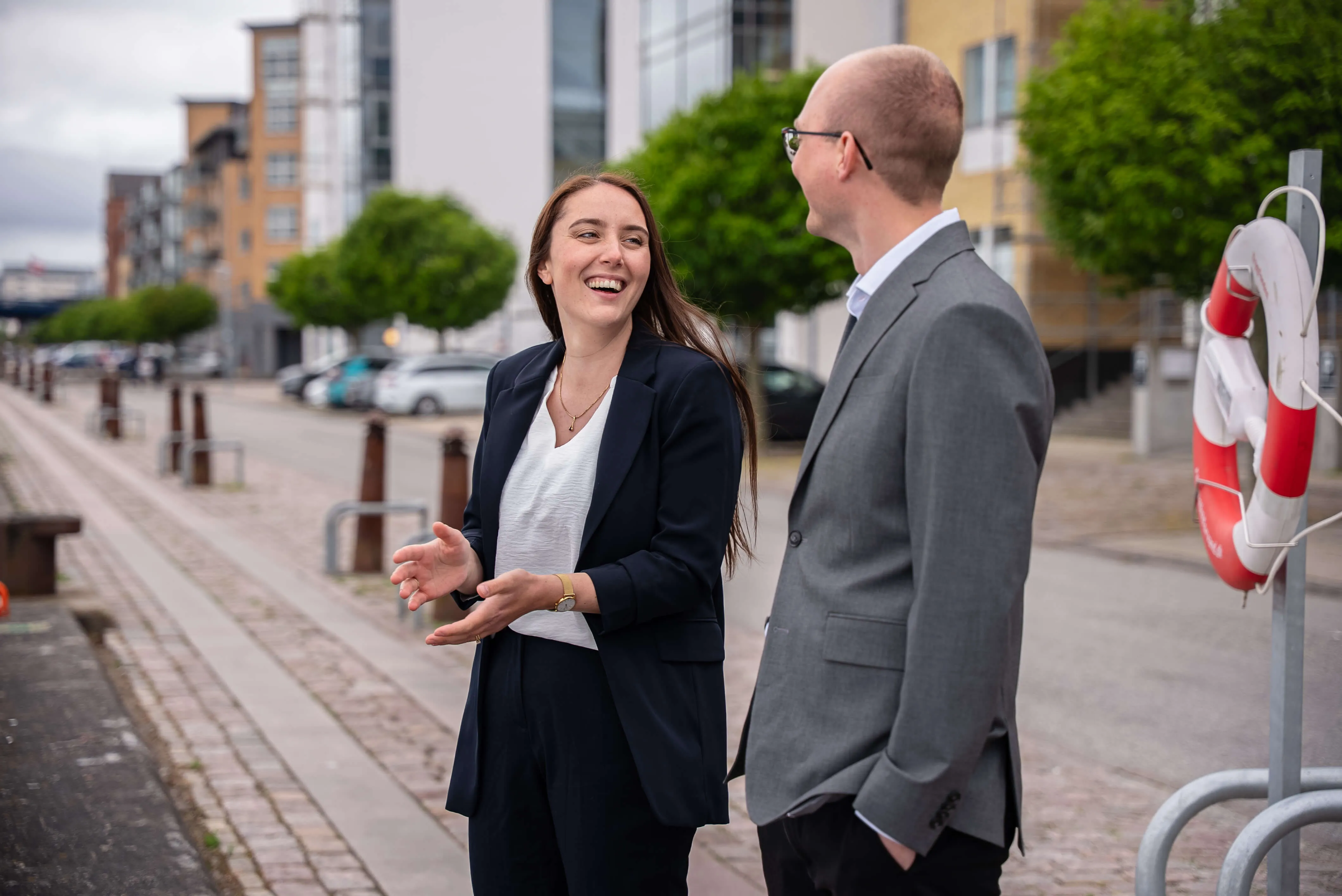 Kvinde og mand står ved en bred. Kvinde griner som om hun lige har fortalt en joke