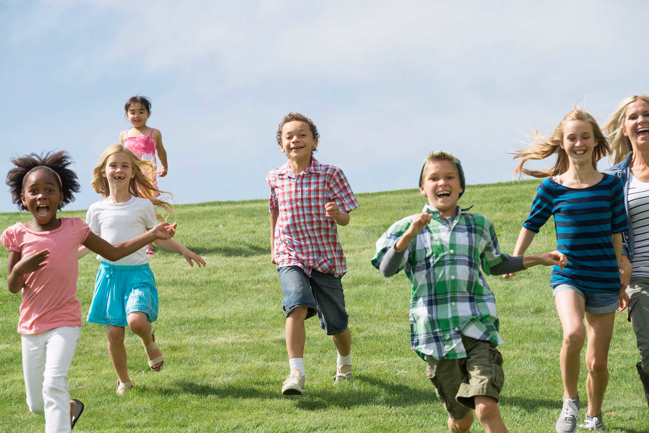 Diverse group of children running and playing together on grassy field