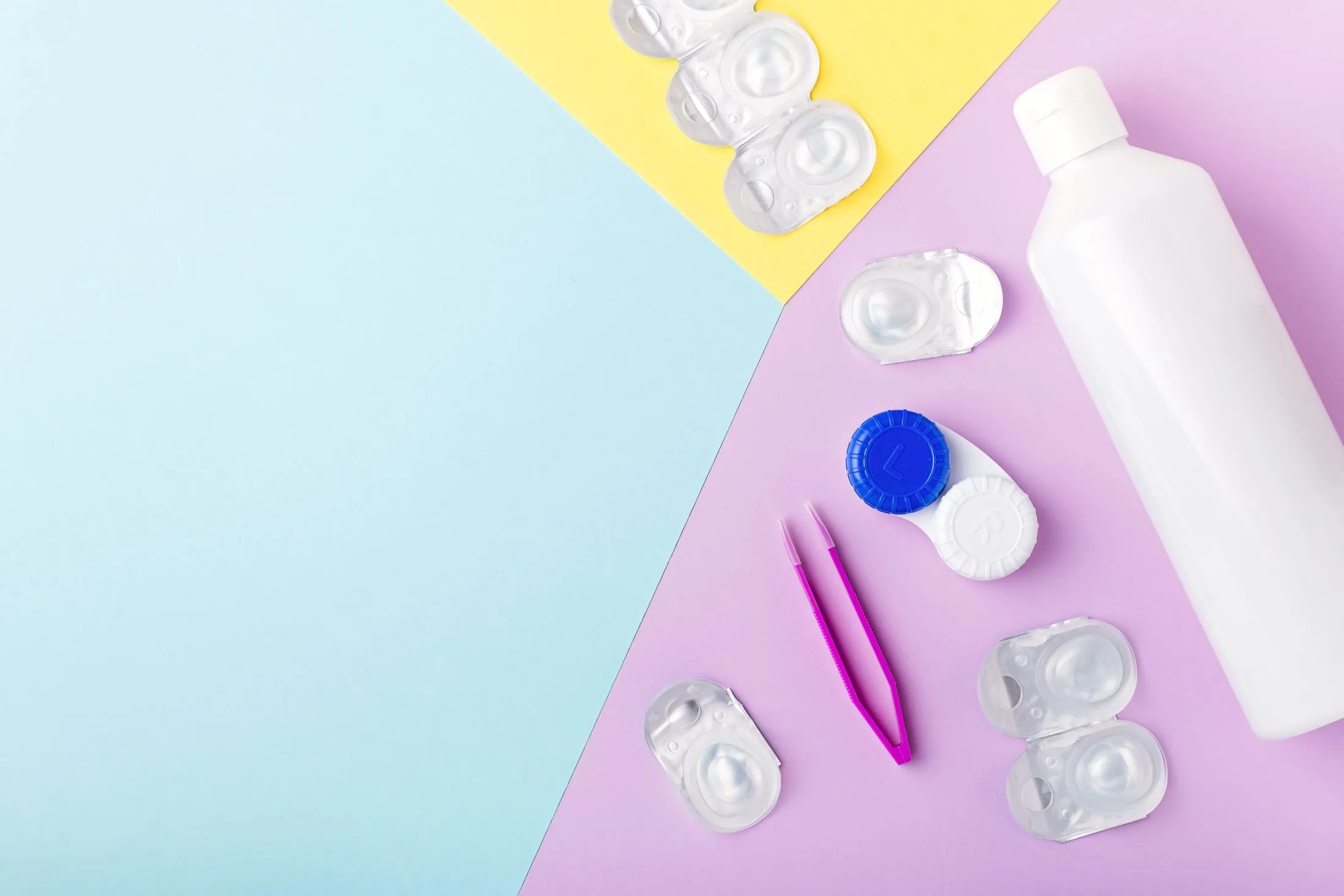 Contact lens supplies on pastel background with white bottle and tweezers