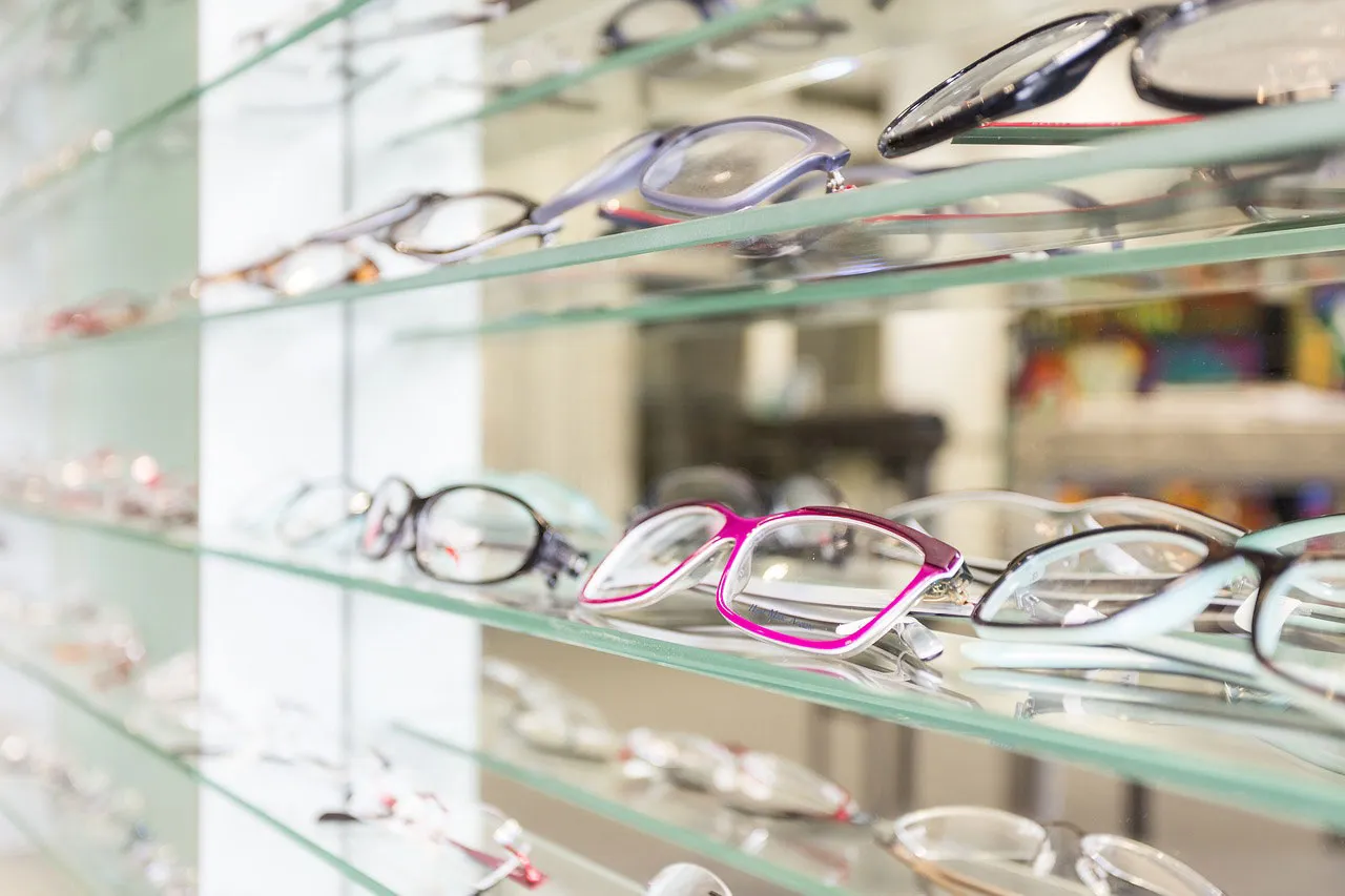 Eyeglasses displayed on glass shelves in an optical store