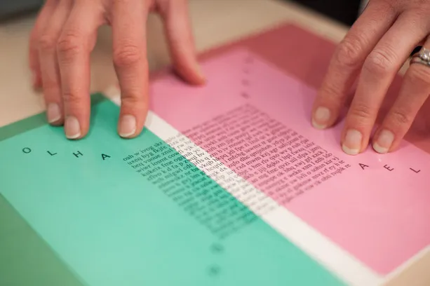 Hands on green and pink document with printed text and border