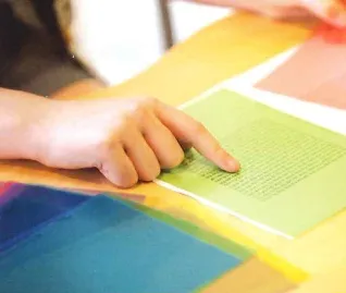 Hand touching colorful paper with text, close-up of learning or reading