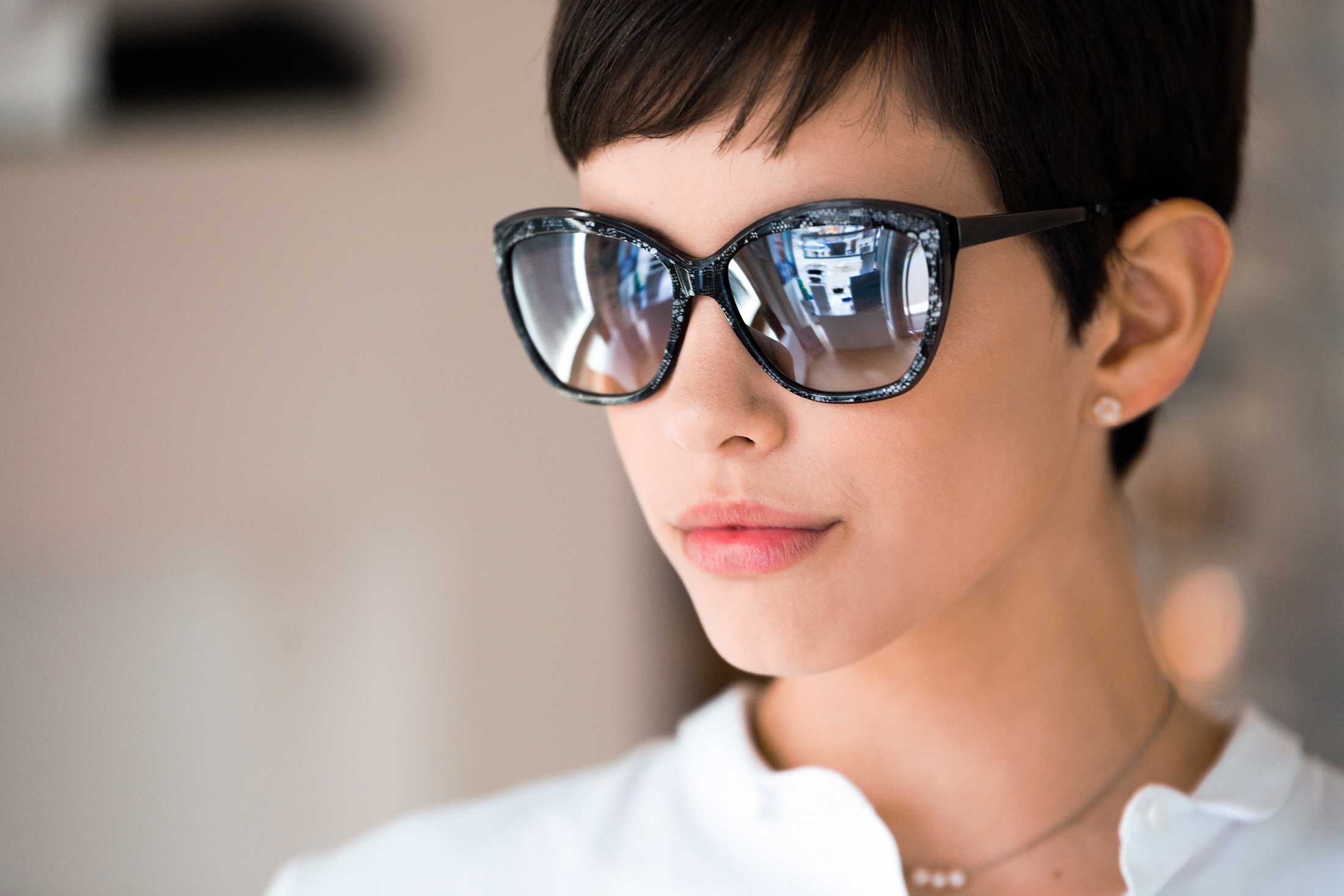 Person with short hair wearing large black cat-eye sunglasses