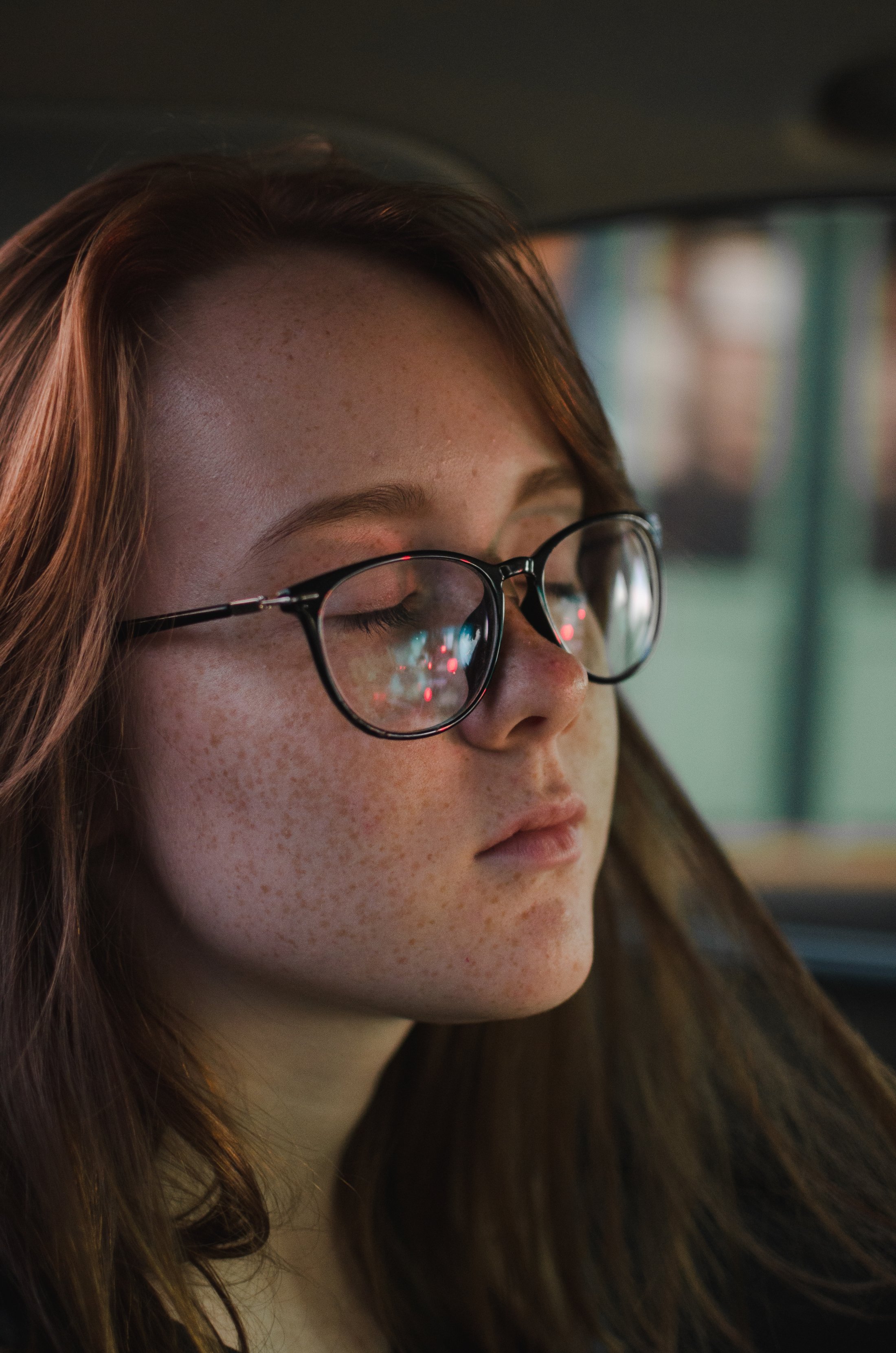 Pensive woman with glasses and freckles looking off into distance