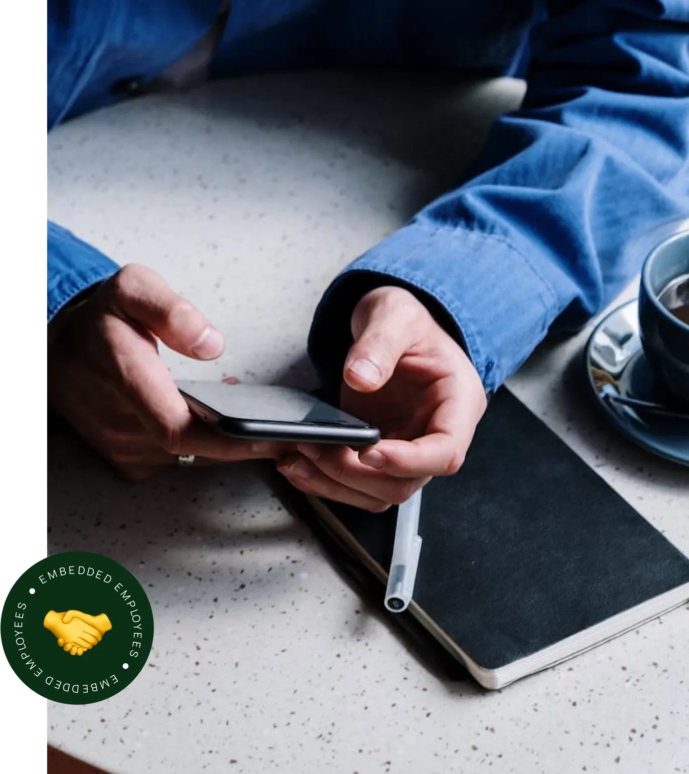 A person sitting at a table using a cell phone.