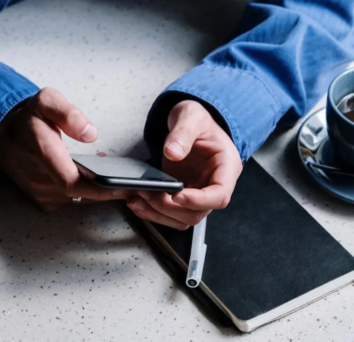 A person sitting at a table using a cell phone.