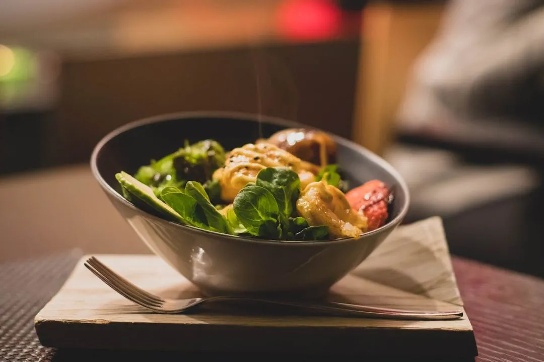 A bowl of food sitting on top of a wooden table.