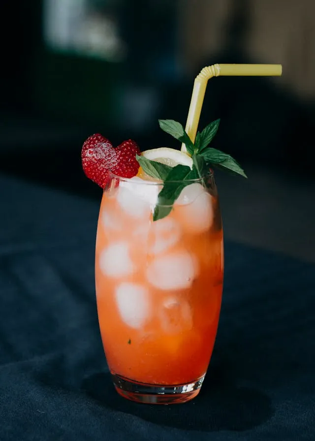 A drink with strawberries and ice in a glass.