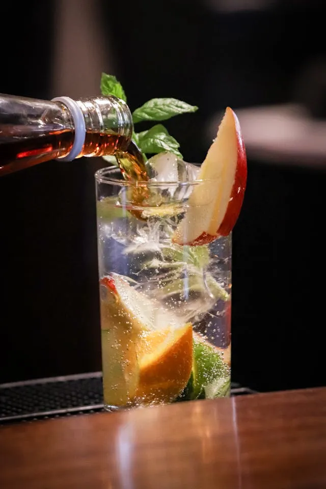 A glass filled with water and fruit on top of a table.