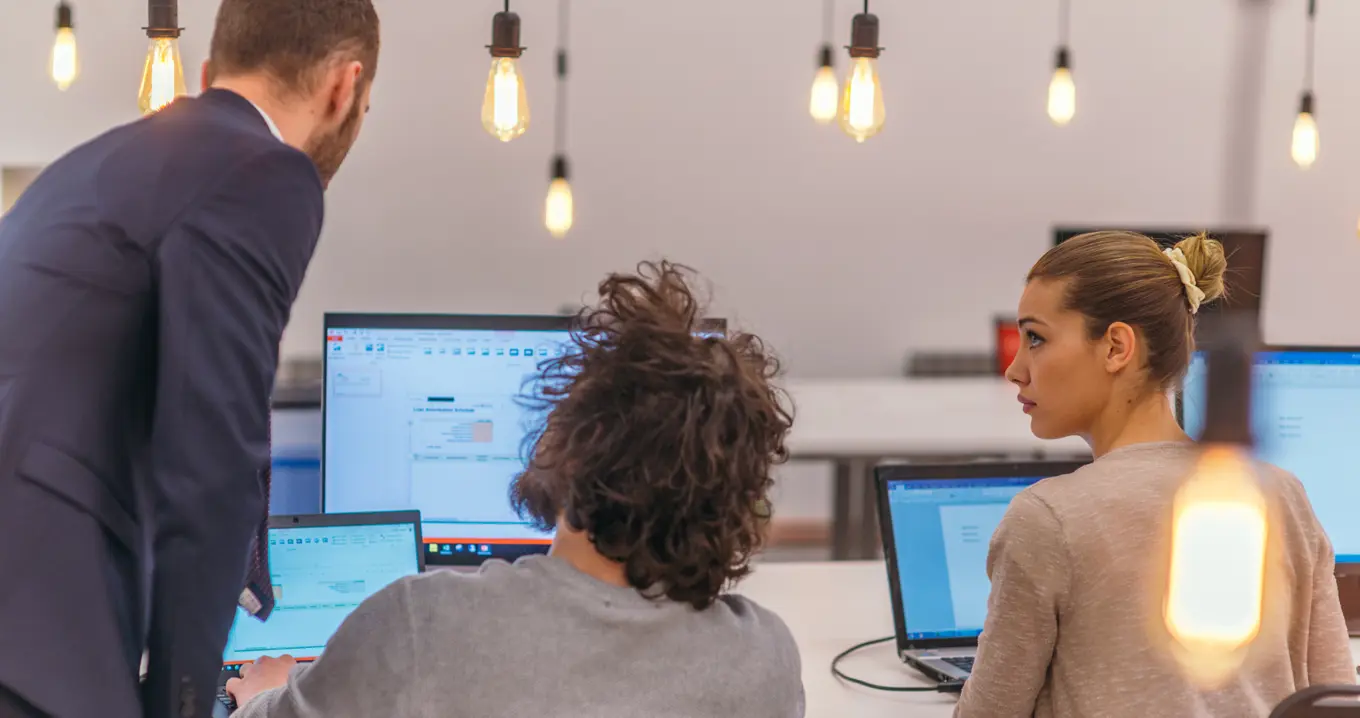 Team of professionals collaborating at computers in a modern office.