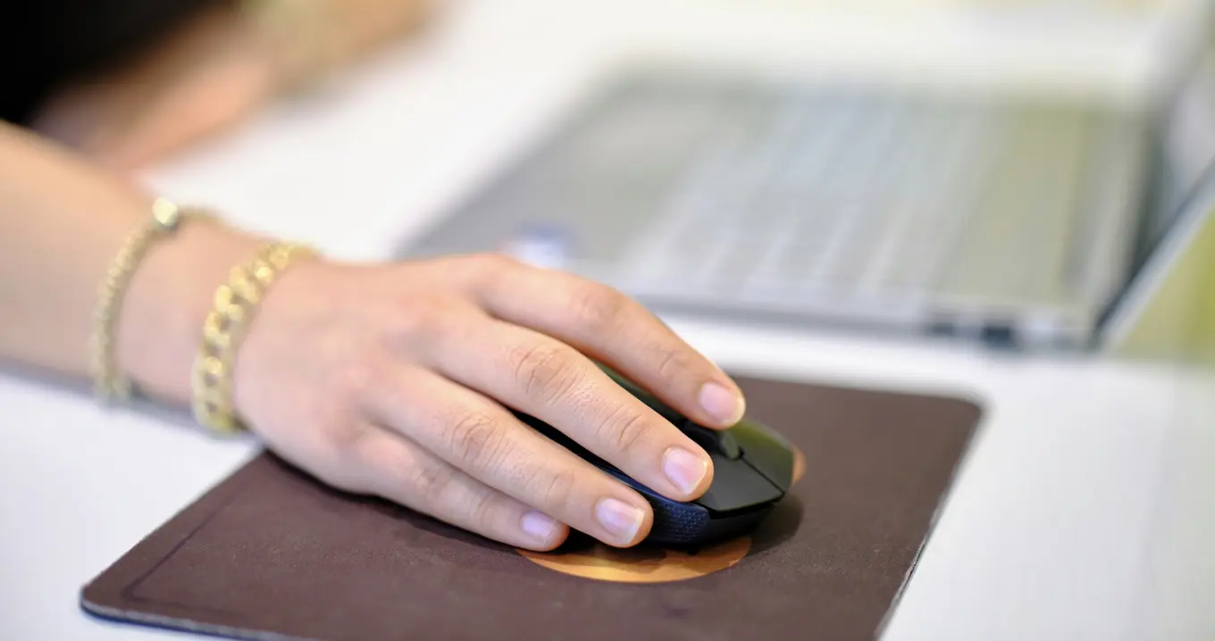 Hand använder datormus vid bärbar dator – symbol för digitalt arbete, användarvänlighet och UX.