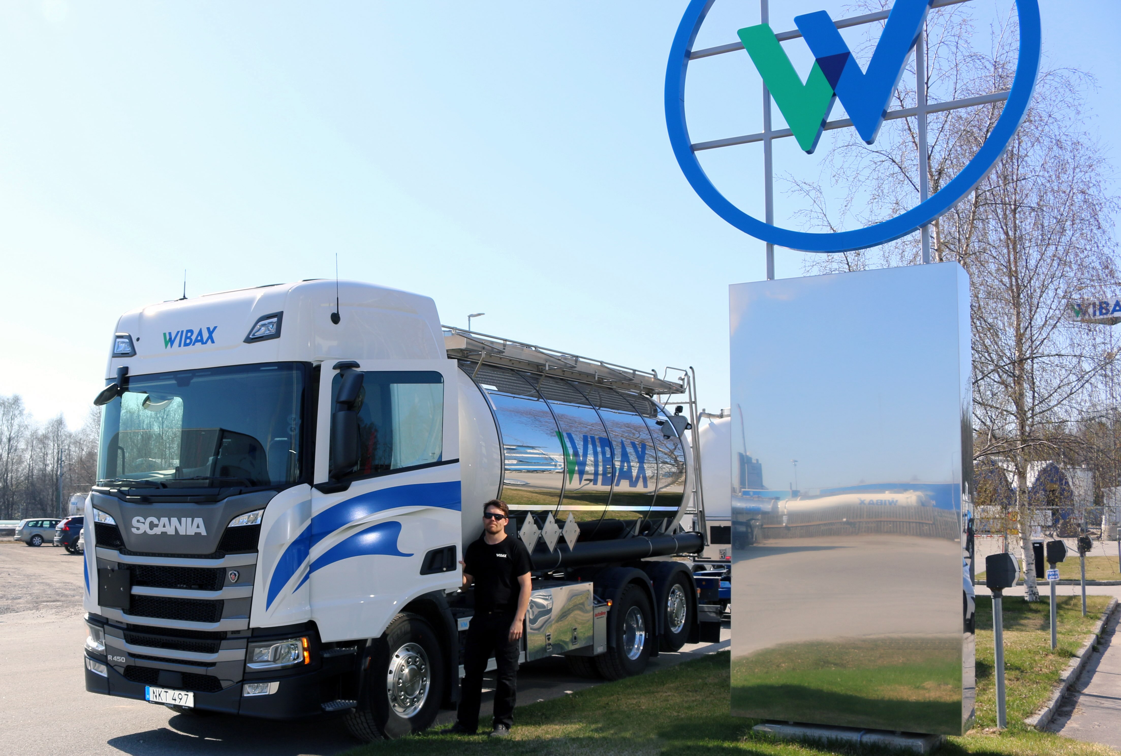 Wibax tankbil och chaufför, symbol för kemikalieleverantörens hållbara logistiklösningar inom import, produktion och distribution av flytande kemiska produkter. Miljömedvetenhet och digital styrning med Hypergene stärker verksamheten.