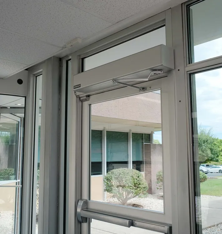 Glass commercial door with a silver door closer and push bar