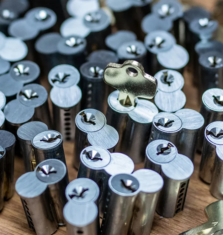 Close-up of multiple metal lock cylinders with one lock pick key inserted into a cylinder