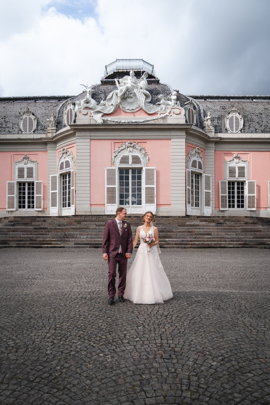 Brautpaar läuft Hand in Hand vor Schloss Benrath in Düsseldorf – elegante Hochzeitsreportage NRW