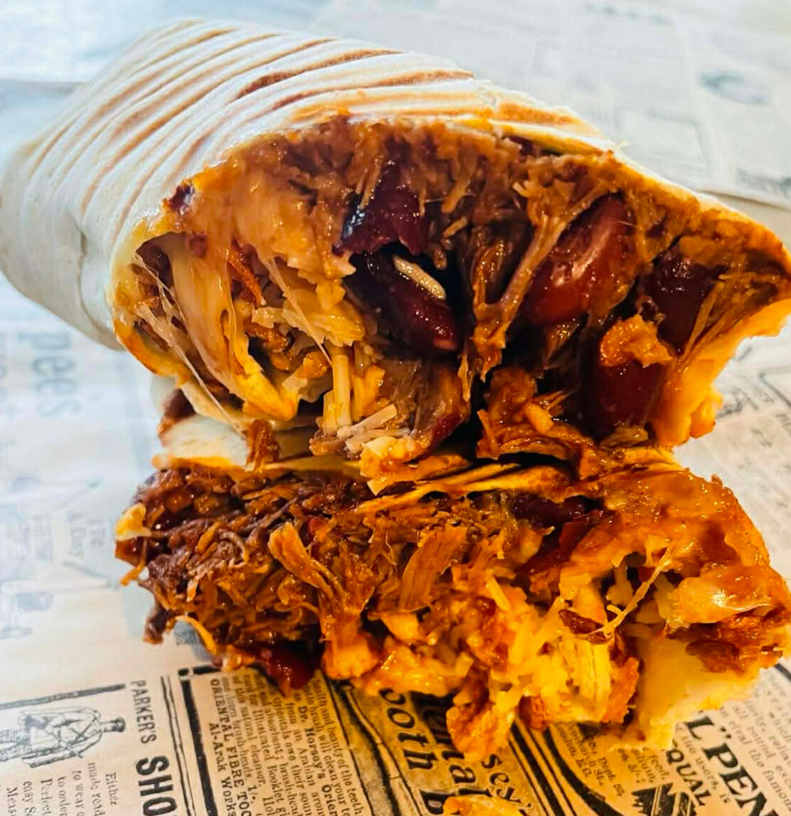 Burrito coupé en deux dévoilant un mélange de riz, viande effilochée et haricots rouges.
