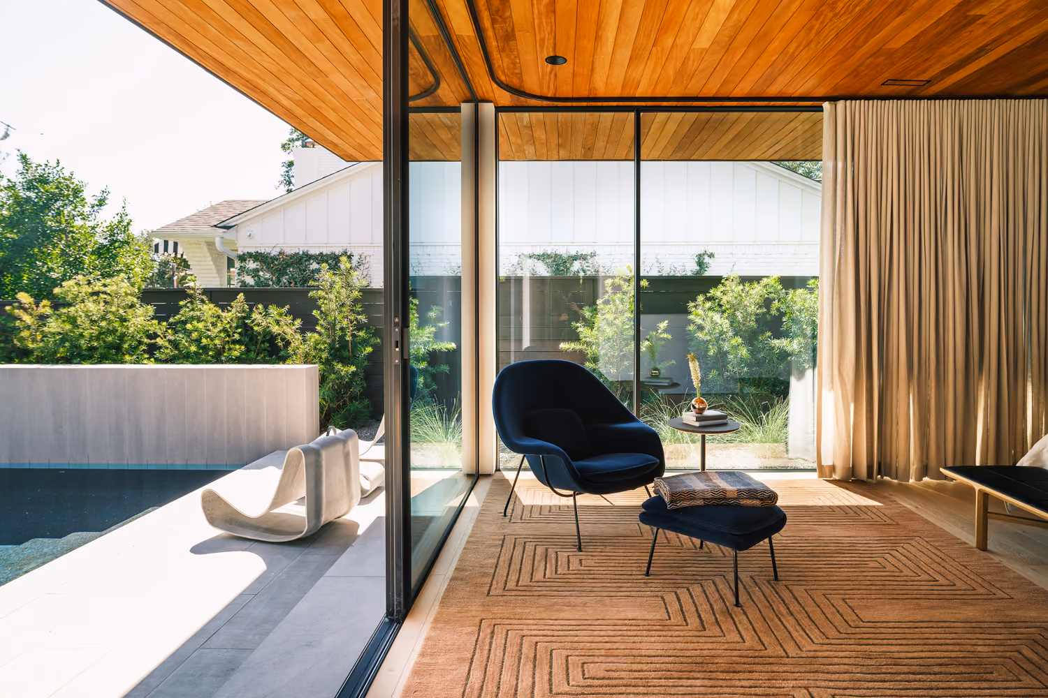 Modern living room with beautiful blue chair and stunning outdoor pool area views.