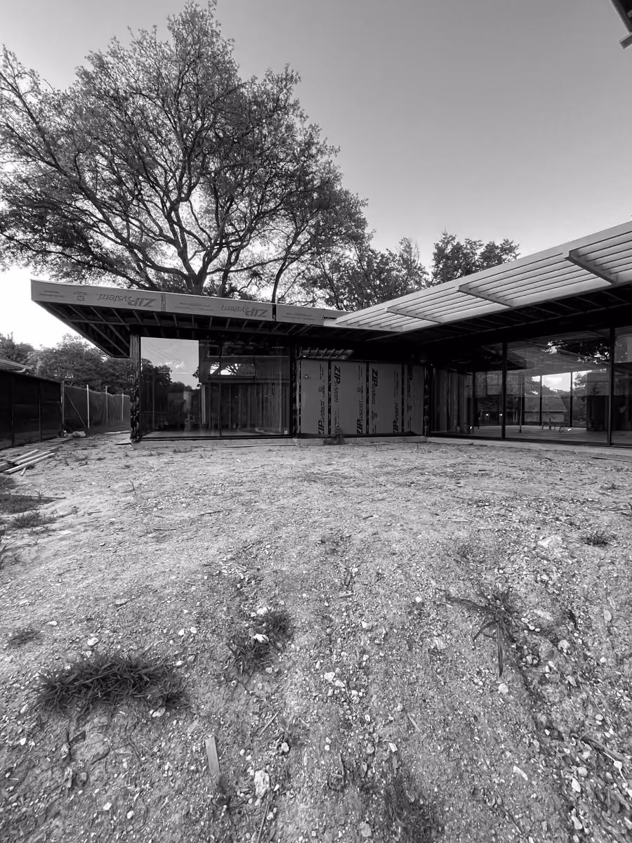 New suburban modern home under construction with large tree and outdoor space.