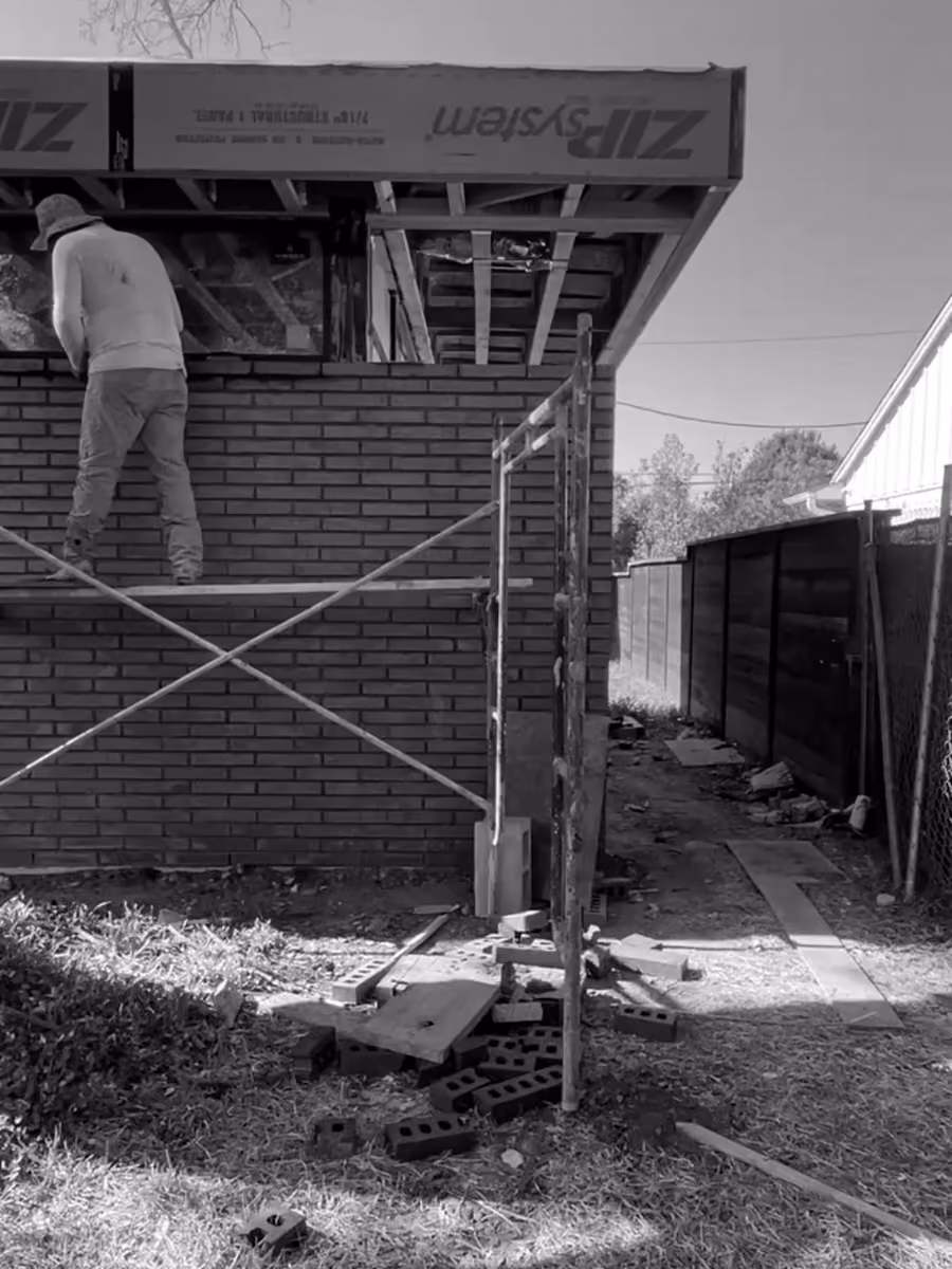 Bricklayer constructing exterior wall on scaffolding at an outdoor construction and building site