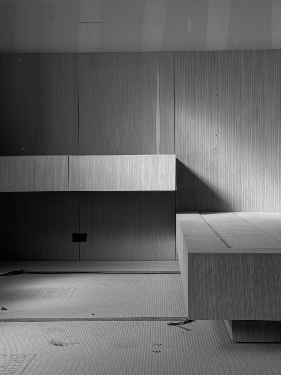 Warm modern minimalist living space with wooden paneling and concrete seating area design.