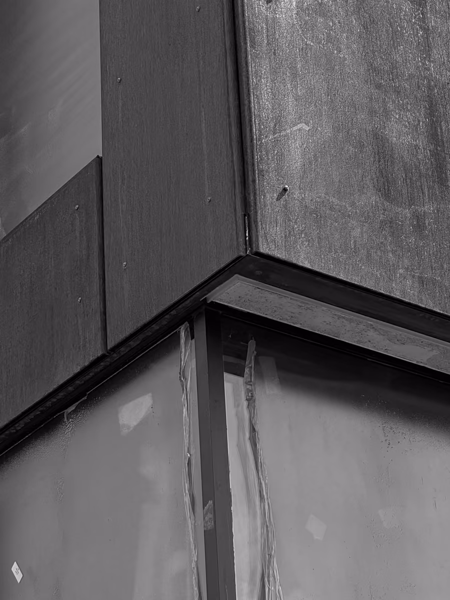 Gray building corner with metal panel and window exterior detailing closely inspected architecture.