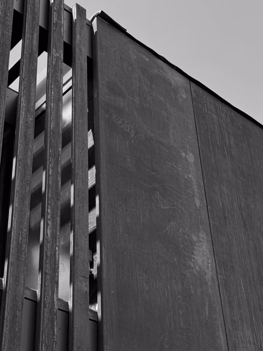 Modern dark gray building exterior with vertical slats and sleek metal panels.