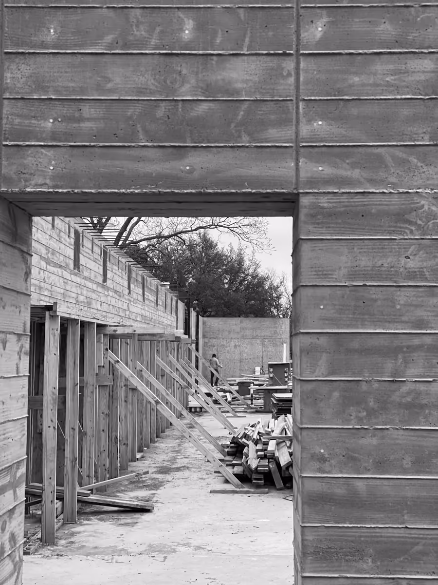 Construction site with wooden structures, building materials, and equipment scattered outside on site.