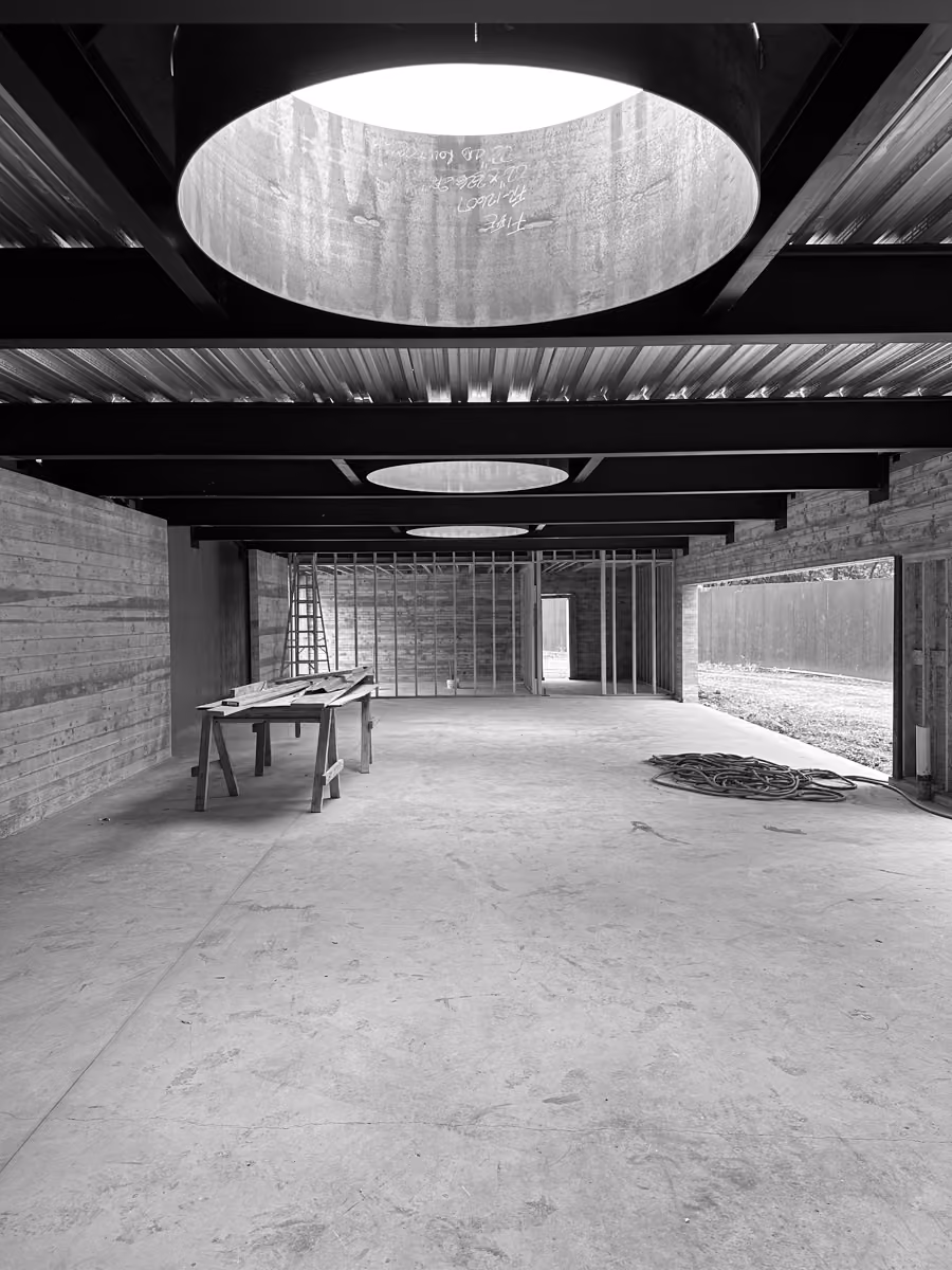 Construction site interior featuring circular skylights amidst unfinished wooden framing and construction supplies nearby