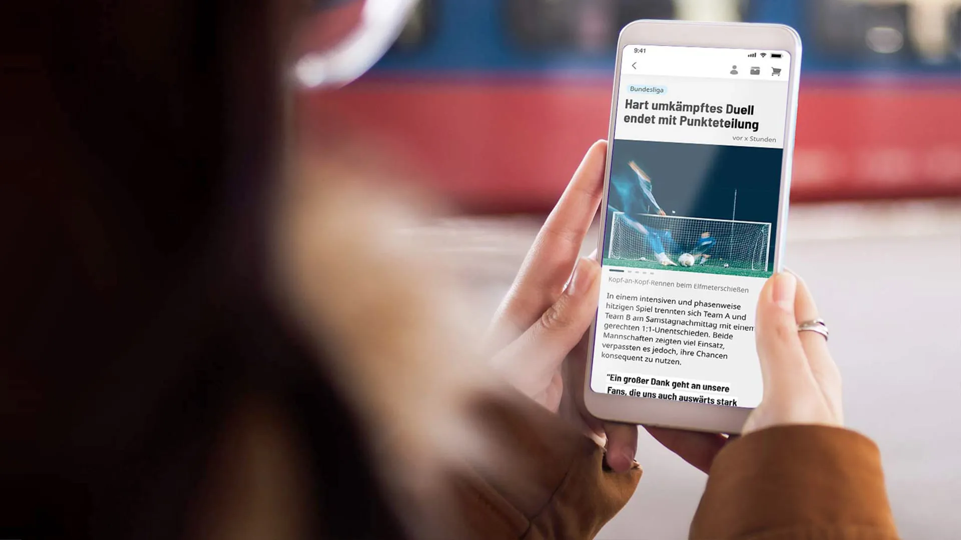 Person hält ein Smartphone, auf dem ein Fußballnachrichtenartikel über ein Unentschieden nach Elfmeterschießen angezeigt wird.