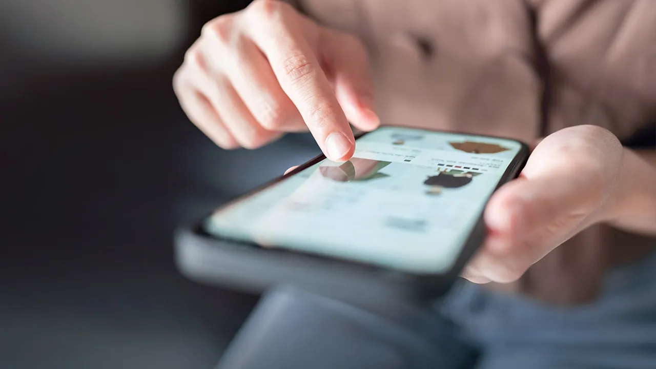 Hand tippt auf Smartphone-Bildschirm mit einer Online-Shop-Anwendung.