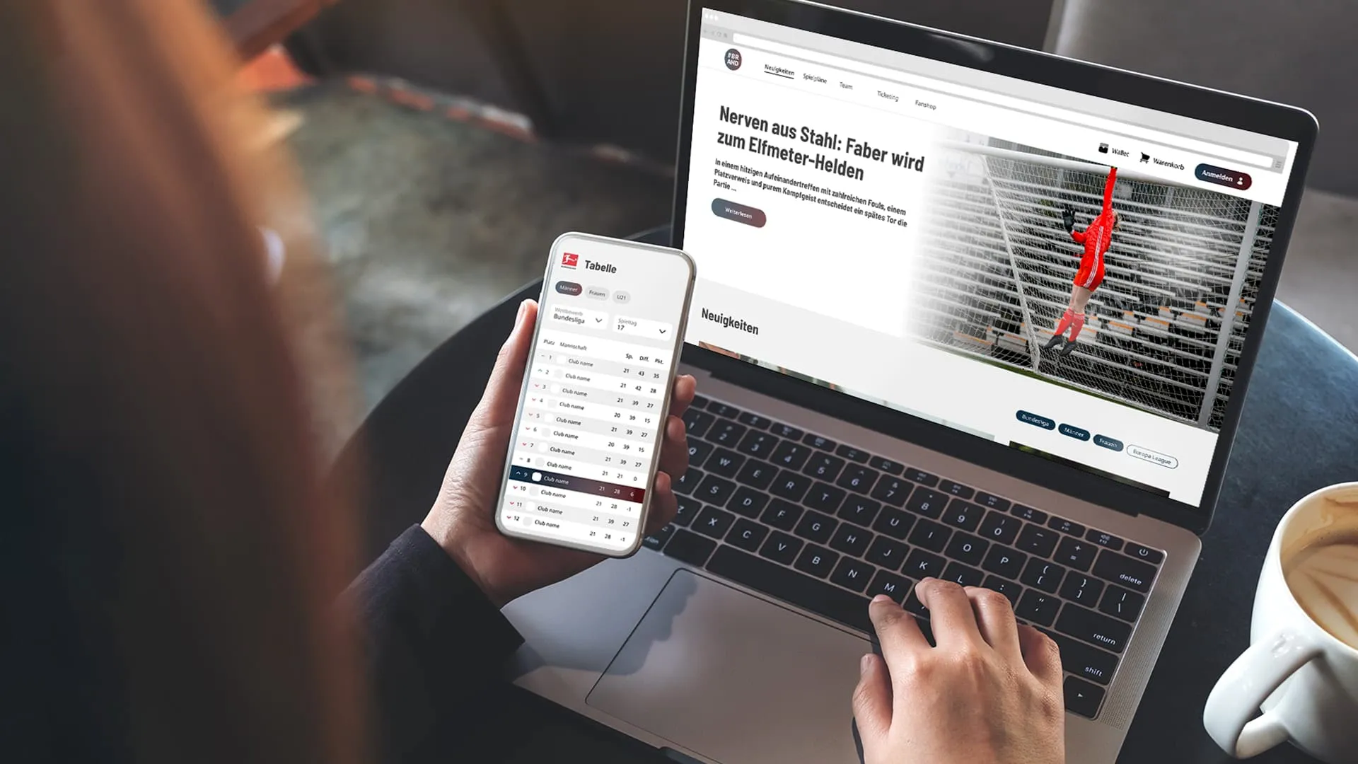 Person sieht auf Laptop mit Sportsnachrichten und hält Smartphone mit Bundesliga-Tabellenübersicht.