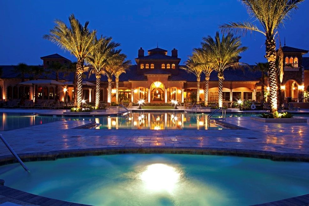 Luxurious resort with illuminated palm trees and reflective swimming pool at night
