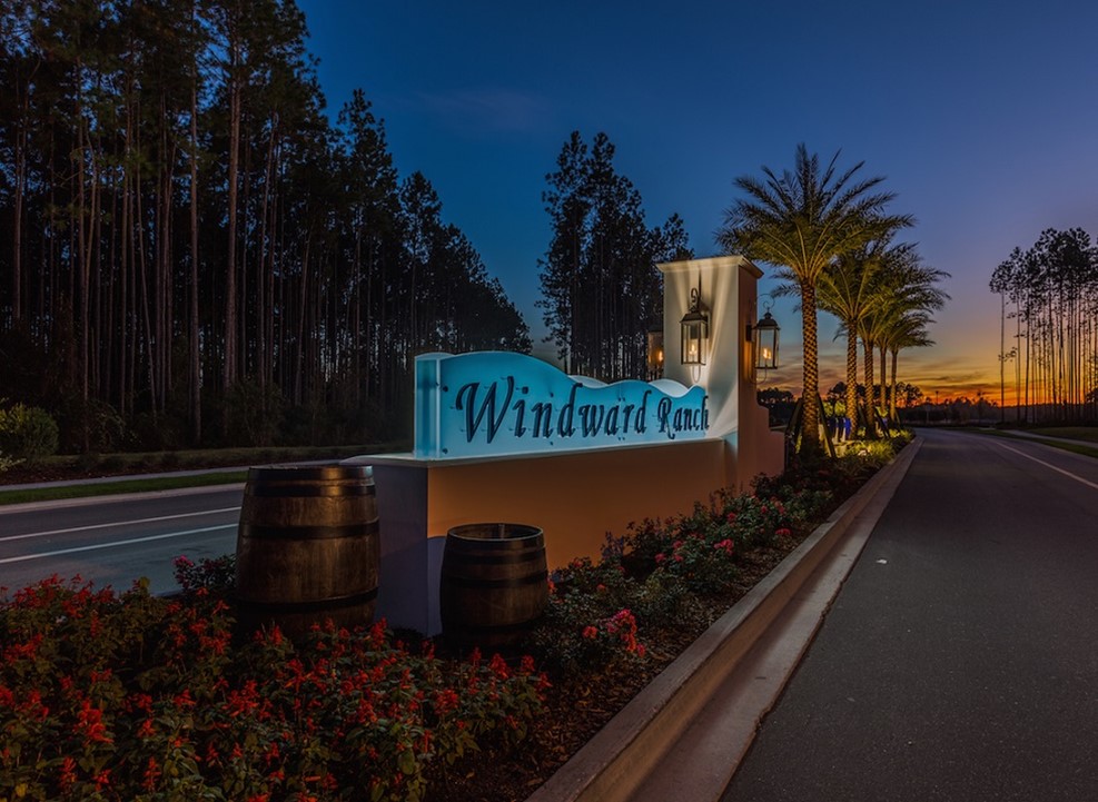 Windward Ranch entrance sign at sunset with decorative barrels and flowers