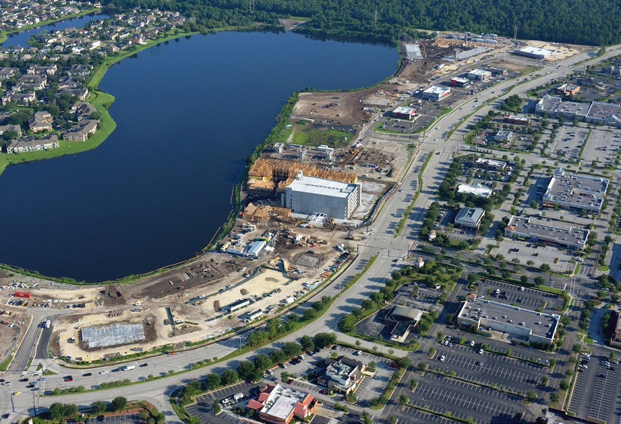 Aerial view of lakeside urban development with construction sites and roads