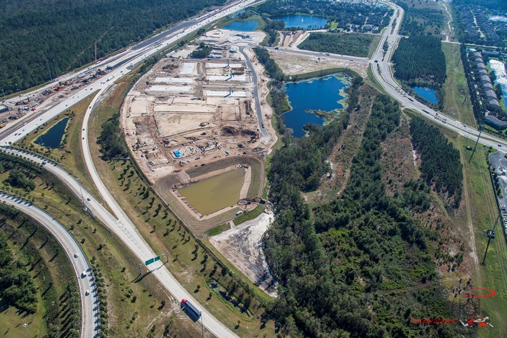 Aerial view of construction site with highways, blue lakes, and forested areas