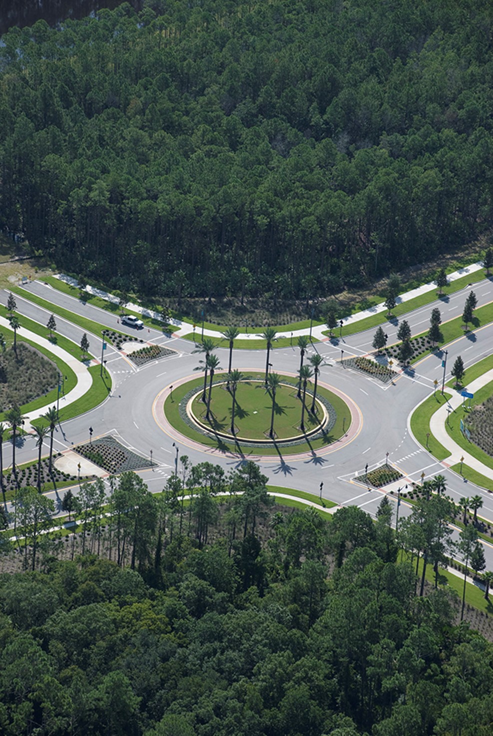 Aerial view of circular roundabout with palm trees amid dense forest