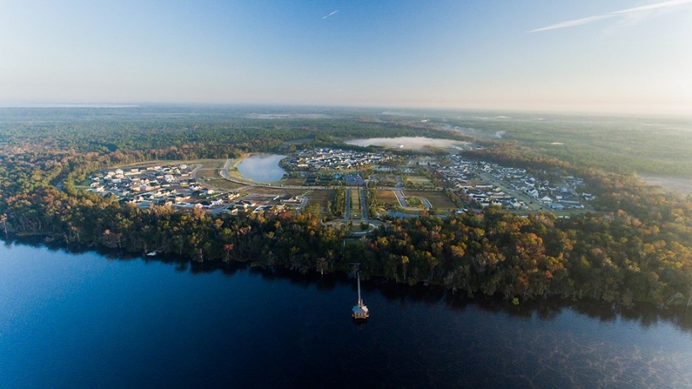 Aerial view of lakeside community surrounded by autumn forest and water