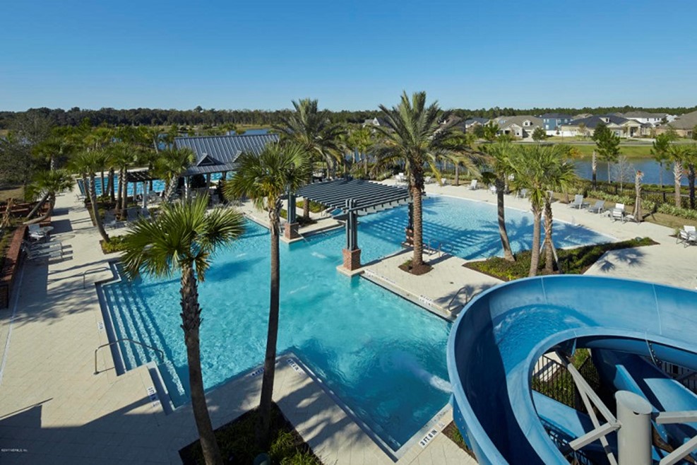 Resort swimming pool with palm trees, water slide, and pergola