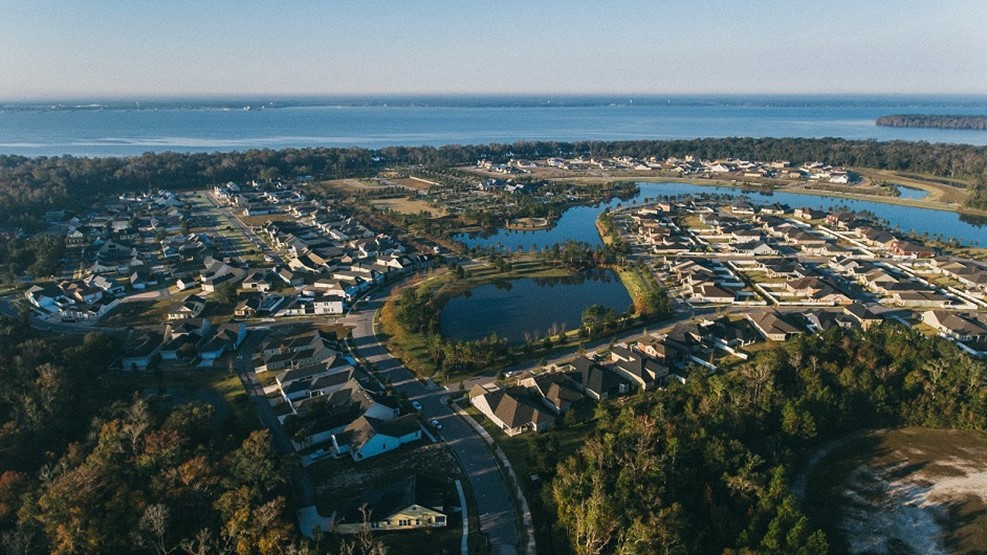 Aerial view of coastal suburban neighborhood with lakes and ocean backdrop