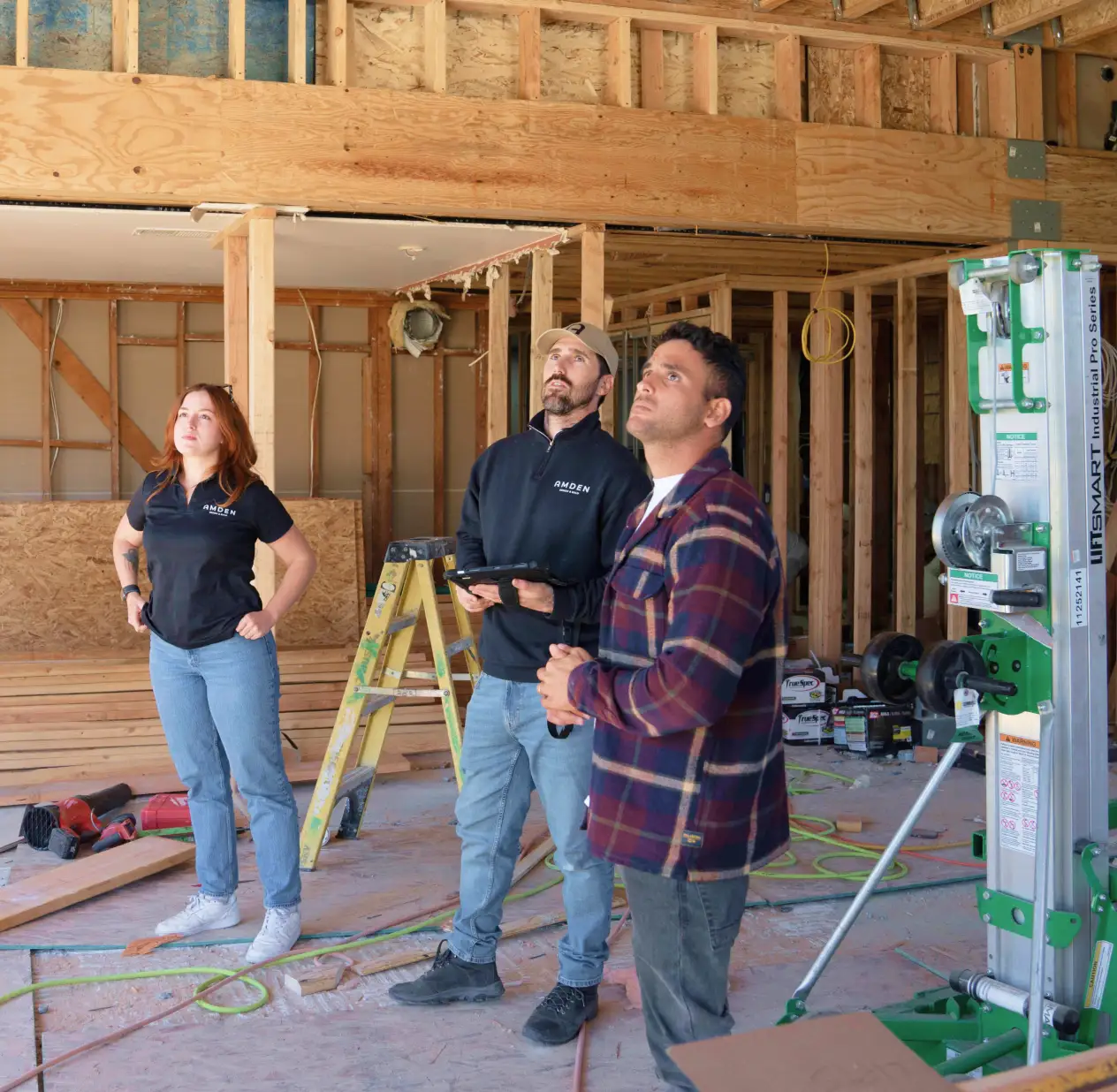 Construction team reviewing plans inside a framed residential project
