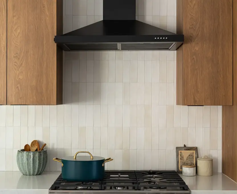 Kitchen stove with black range hood wood cabinets and light tile backsplash