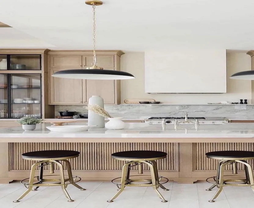 Light wood kitchen with marble island black stools and modern pendant lighting