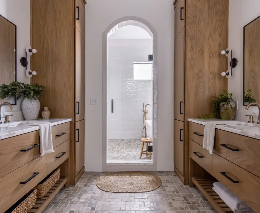 Warm wood double vanity bathroom with arched entry to shower and neutral tones